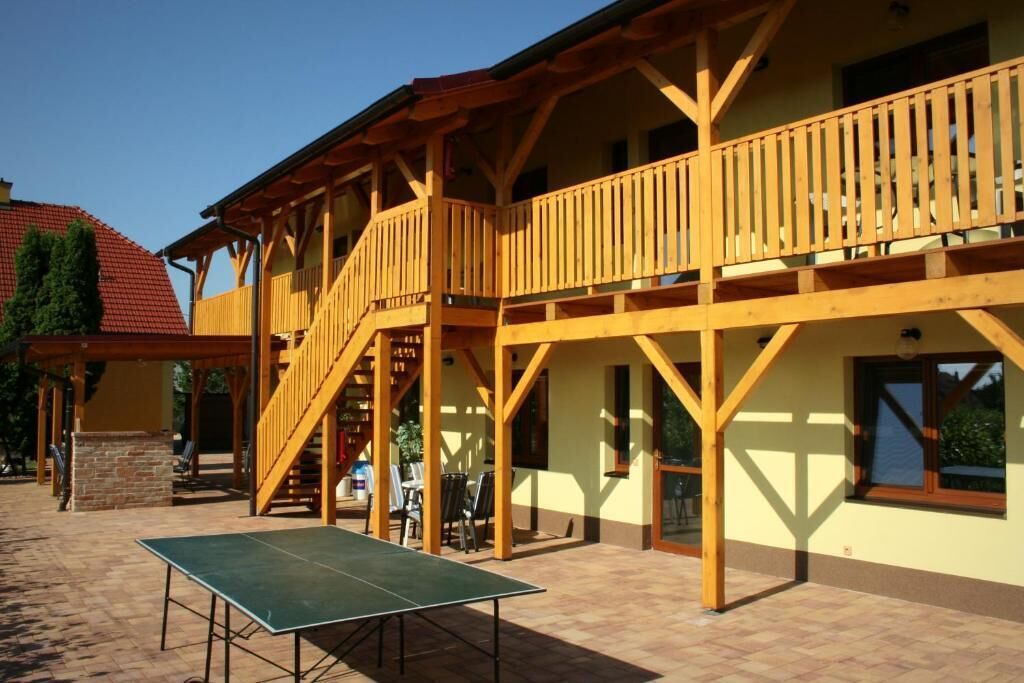 A building with a wooden balcony, a ping pong table, and a staircase leading to an upper level.