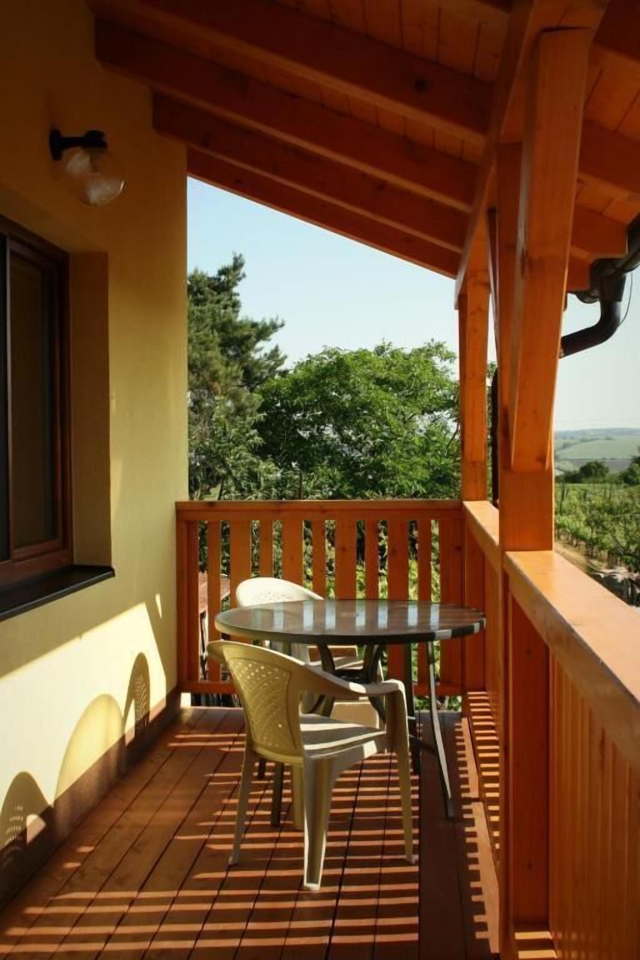 Une terrasse en bois avec une table et des chaises, offrant une vue sur un paysage luxuriant.