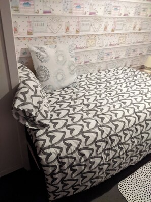 Un lit avec une couvre-lit à motifs, un oreiller et un mur recouvert d’un papier peint décoratif.