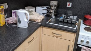 Eine Küche mit Holdekor, einer Arbeitsplatte aus Granit, einem Wasserkocher, einem Toaster, einem Herd und einem Spülbecken.