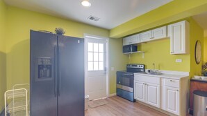 A kitchen with a black refrigerator, white cabinets, a stove, and a microwave.