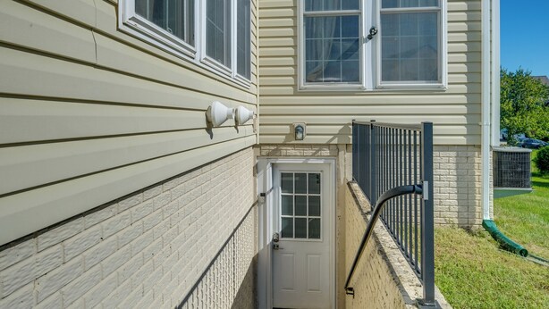 A house with a white door, a small front porch, and a black metal fence.