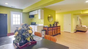 A dining area with a table set for two, a vase of flowers, and a wooden cabinet in the background.