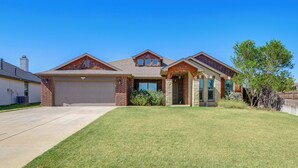 A two-story house with a garage, a front porch, and a well-maintained lawn. - 11 Mi to Dtwn: Lubbock Home w/ Patio, Grill & Yard (Lubbock)