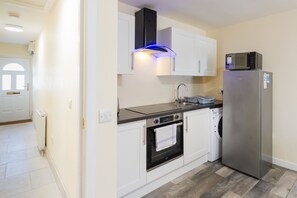 A compact kitchen with white cabinets, a stainless steel refrigerator, a built-in oven, and a microwave. - Central 2-Bed Flat near Edinburgh’s Highlights (Edinburgh)