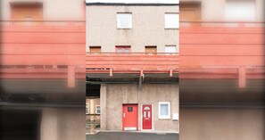 A building with a red door, a window, and a small balcony.