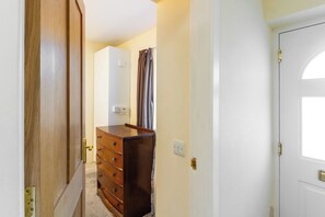 A hallway with a wooden door, a white wall, and a brown dresser with drawers.