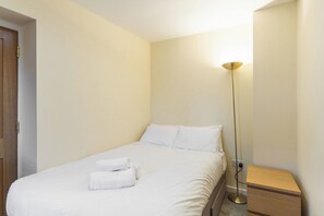 A hotel room with a bed, a bedside table, a floor lamp, and a door. - Central 2-Bed Flat near Edinburgh’s Highlights (Edinburgh)
