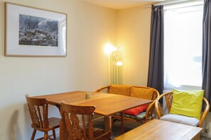 A dining area with a wooden table and chairs, a framed picture on the wall, and a floor lamp.