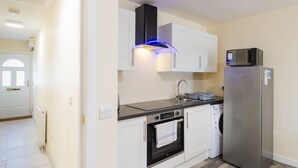 A compact kitchen with white cabinets, a stainless steel refrigerator, a built-in oven, and a microwave. - Central 2-Bed Flat near Edinburgh’s Highlights (Edinburgh)