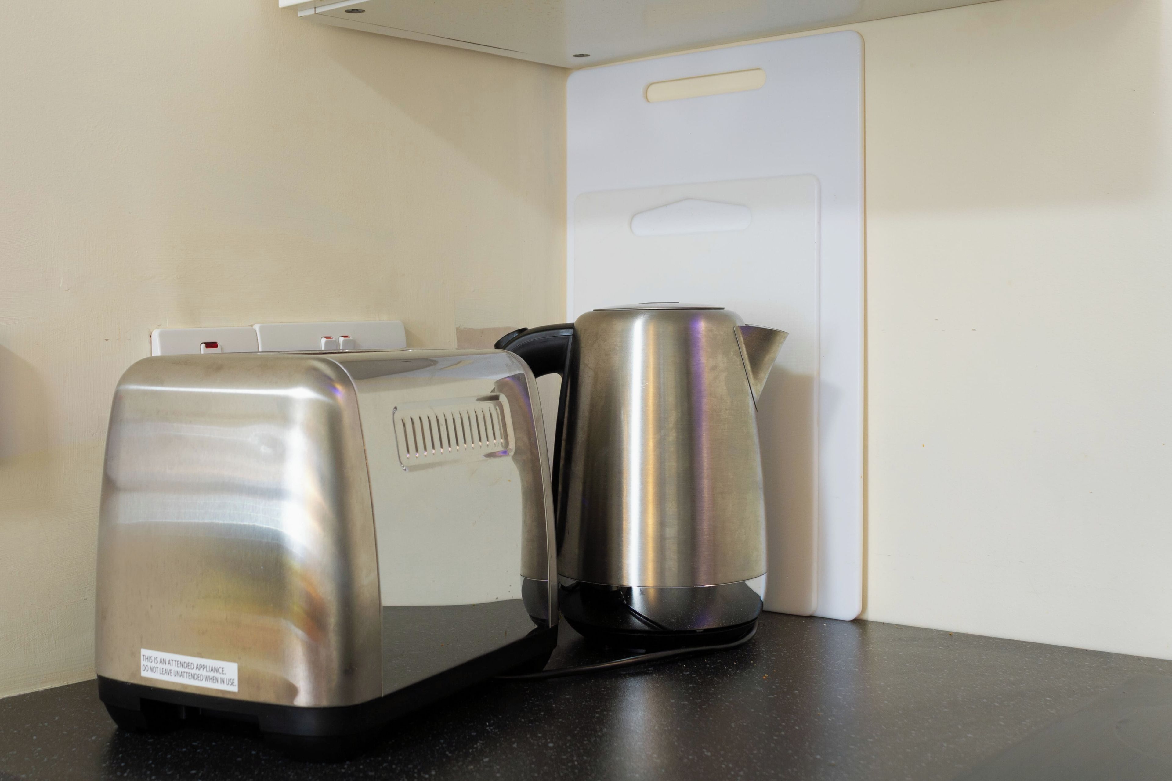 A kitchenette with a coffee maker and a kettle on a countertop.