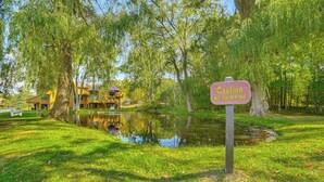 A sign warning of no swimming in a park with a pond, surrounded by trees and a building in the background. - 7 Mi to Dwtn - Family Condo in Harbor Springs! (Harbor Springs)