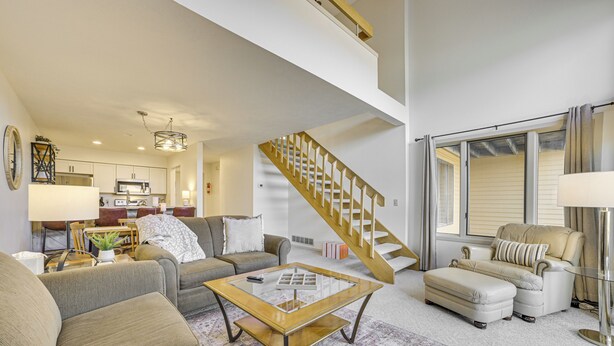 A spacious living room with a high ceiling, a staircase, and a kitchen in the background. - 7 Mi to Dwtn - Family Condo in Harbor Springs! (Harbor Springs)