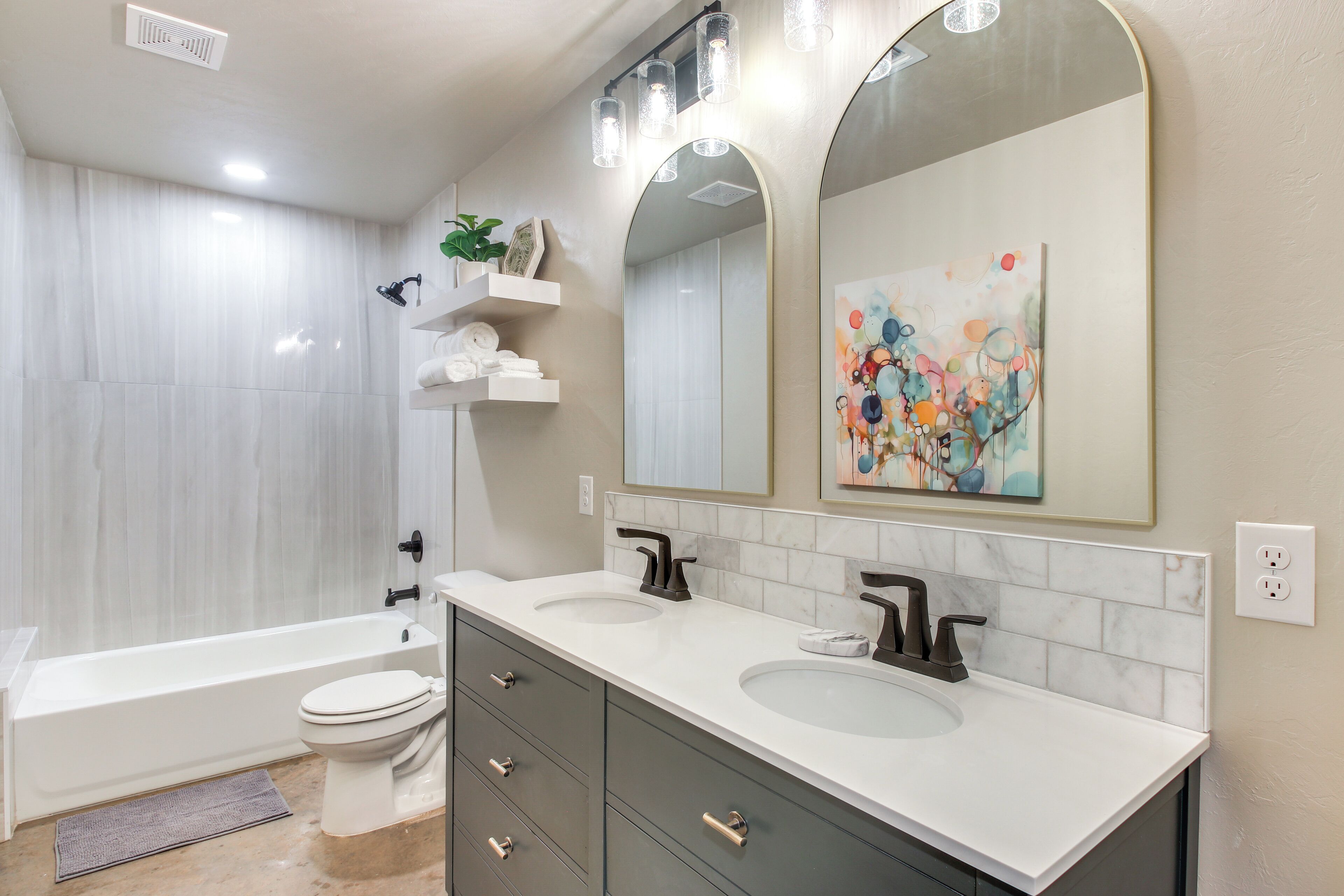 A modern bathroom with two sinks, a bathtub, and a large mirror.