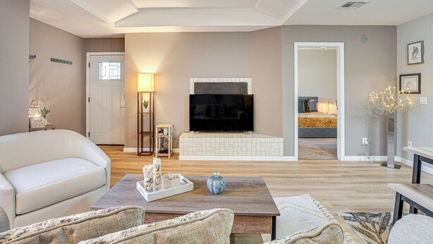 A living room with a sofa, coffee table, and a TV in the background.