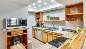 A modern kitchen with wooden cabinets, a built-in microwave, and a large island with a sink.