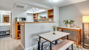 A modern kitchen with built-in appliances, wooden shelving, and a dining area with a bench.