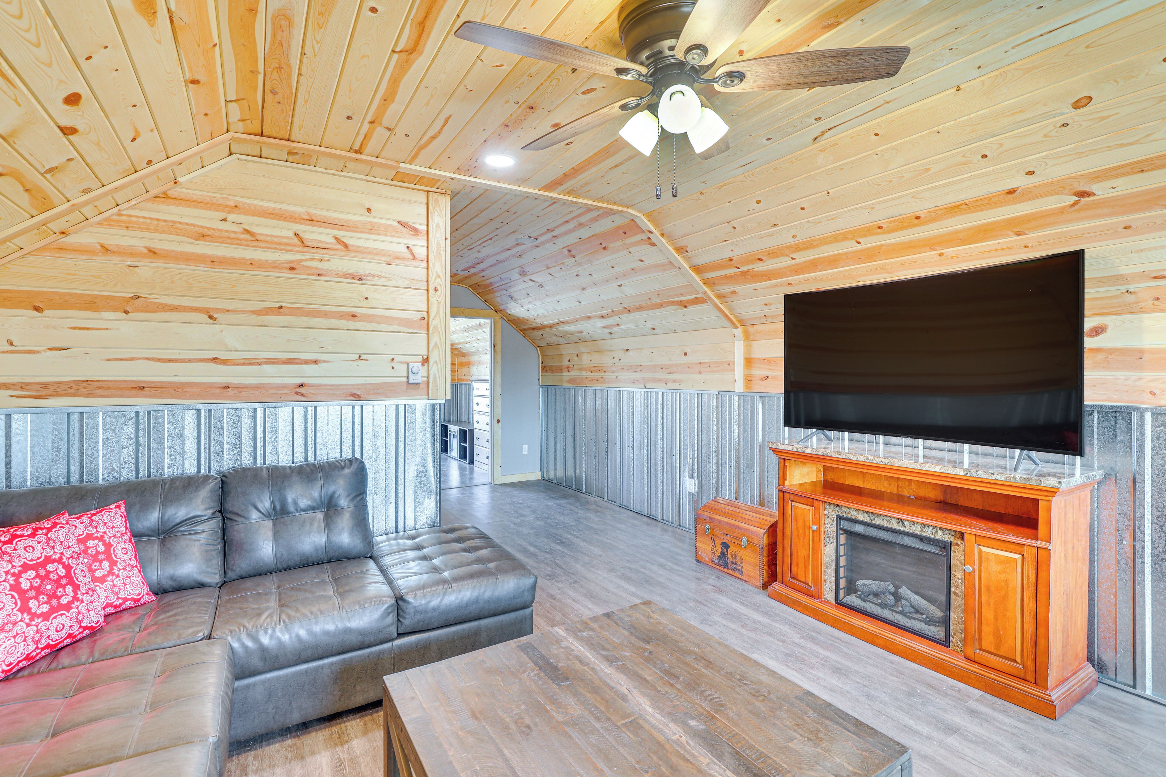 Amplia sala de estar con un sofá de cuero, un mueble de entretenimiento de madera y una chimenea.