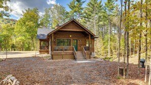 A cabin with a covered porch, a front door, and a staircase leading up to the entrance. - Riverfront Hideaway in Keene: Walk to Town! (Keene)