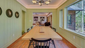 A dining area with a long table, chairs, and a chandelier. - Riverfront Hideaway in Keene: Walk to Town! (Keene)
