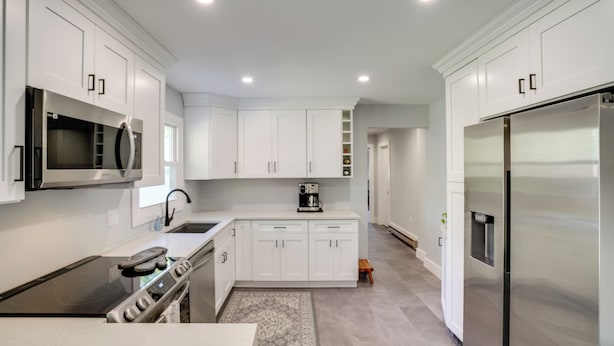 A modern kitchen with white cabinetry, stainless steel appliances, and a central island. - 1 Mi to Dtwn: Cottage w/ Large Yard in Stockbridge (Glendale)