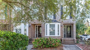 A two-story brick house with a bay window and a front porch. - Walk to Ocean & Dtwn: Myrtle Beach Townhome! (Myrtle Beach)