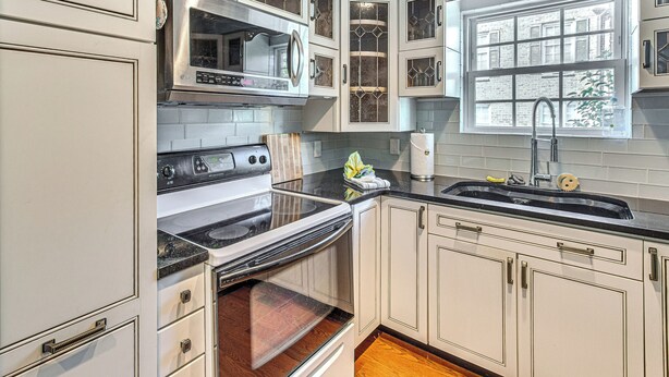 A kitchen with white cabinets, a stainless steel oven, a microwave, and a window with a view of a brick building. - Walk to Ocean & Dtwn: Myrtle Beach Townhome! (Myrtle Beach)