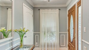 A hallway with a wooden door, a white curtain, and a glass vase with flowers. - Walk to Ocean & Dtwn: Myrtle Beach Townhome! (Myrtle Beach)