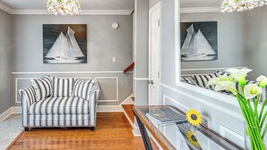 A living room with a striped sofa, a glass coffee table, a vase with flowers, and a sailboat painting on the wall. - Walk to Ocean & Dtwn: Myrtle Beach Townhome! (Myrtle Beach)