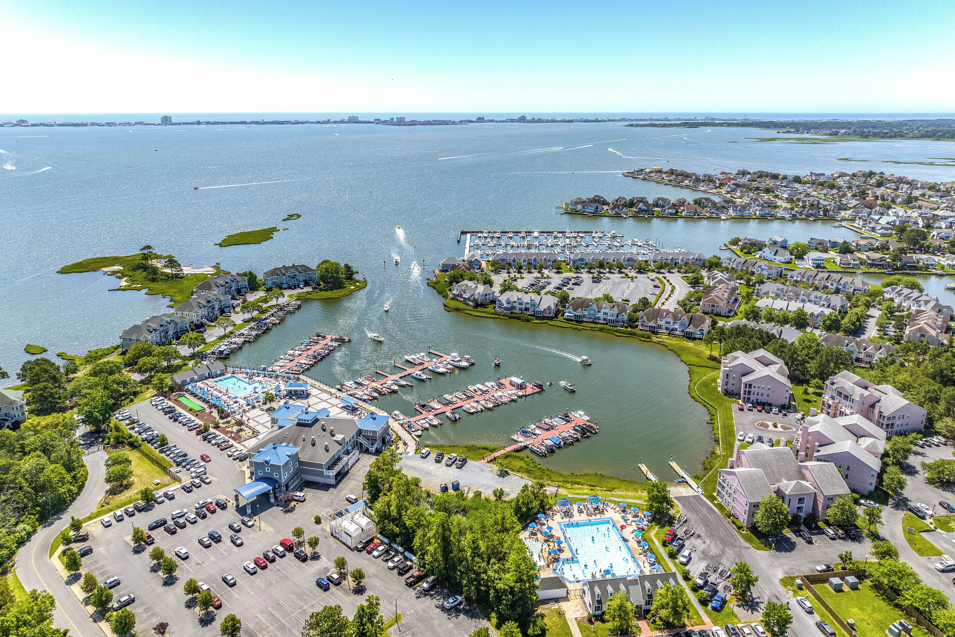 An aerial view of a waterfront property with a marina, swimming pool, and residential buildings.