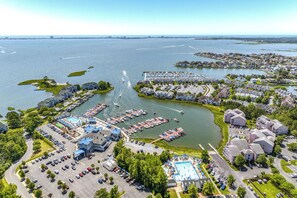 Vue aérienne d’une propriété située au bord de l’eau, comprenant un port de plaisance, une piscine et des immeubles résidentiels.