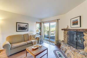Un salon comprenant un canapé, une table basse, une cheminée et une vue sur l’extérieur.