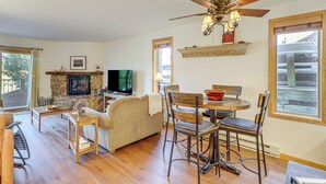 A cozy living room with a fireplace, a television, and a dining area with chairs and a table.