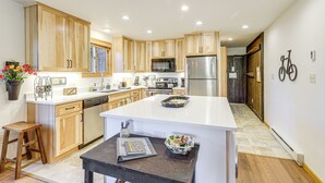 A modern kitchen with wooden cabinets, a central island, and stainless steel appliances.