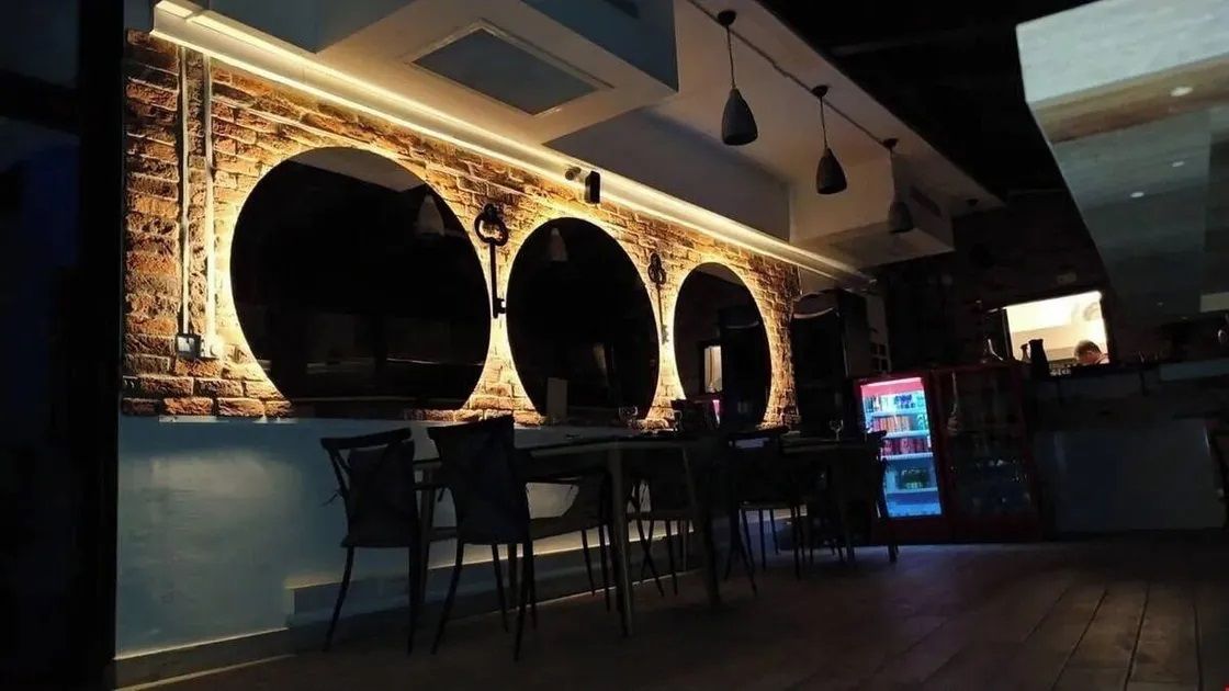 A restaurant with a brick wall, three arches, and a counter.