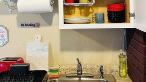 Une cuisine équipée d’un évier, d’un panneau « Il est interdit de fumer » et de divers ustensiles de cuisine.