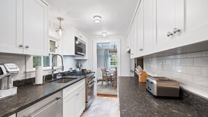 Eine moderne Küche mit weißen Schränken, einer Arbeitsplatte aus Granit, einem eingebauten Backofen und einem Toaster.