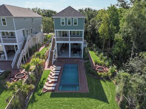 A two-story house with a pool, outdoor seating, and a well-maintained lawn. - 7BR Mississippi Gulf Coast | Heated Pool & Balcony (Bay St. Louis)