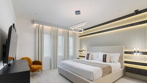 A modern bedroom with a large bed, a TV on a stand, and a desk with a chair. - 5911 Luxury 10bd Family Home For an Unforgettable Vacation (Orlando)