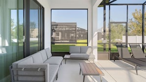 A modern outdoor living space with a sofa, a table, and lounge chairs. - 5911 Luxury 10bd Family Home For an Unforgettable Vacation (Orlando)
