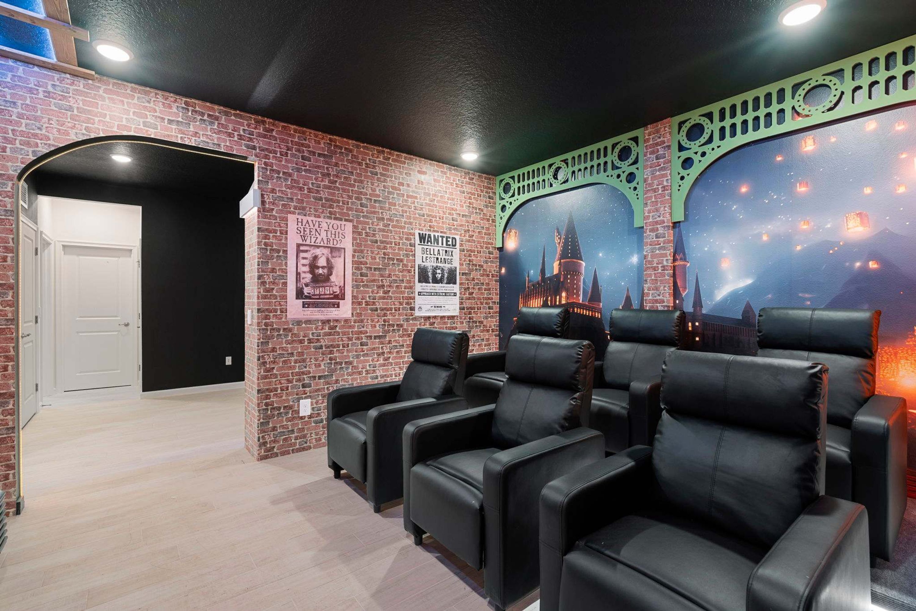 Une pièce aux murs de briques, avec des fauteuils en cuir noir et une affiche représentant un château.