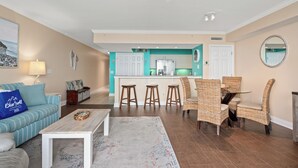 Una sala de estar moderna con sofá, mesa de centro y un comedor con sillas de mimbre y una mesa de vidrio.