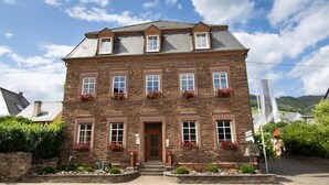 A stone building with a wooden door, multiple windows, and flower boxes. - Weinhof Gassen (Kröv)
