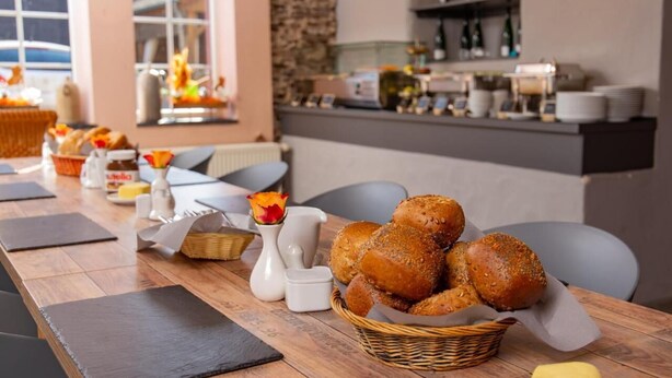 A breakfast buffet setup with bread, butter, and condiments on a wooden table. - Weinhof Gassen (Kröv)