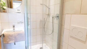 A modern bathroom with a glass-enclosed shower, a white sink, and a toilet. - Weinhof Gassen (Kröv)