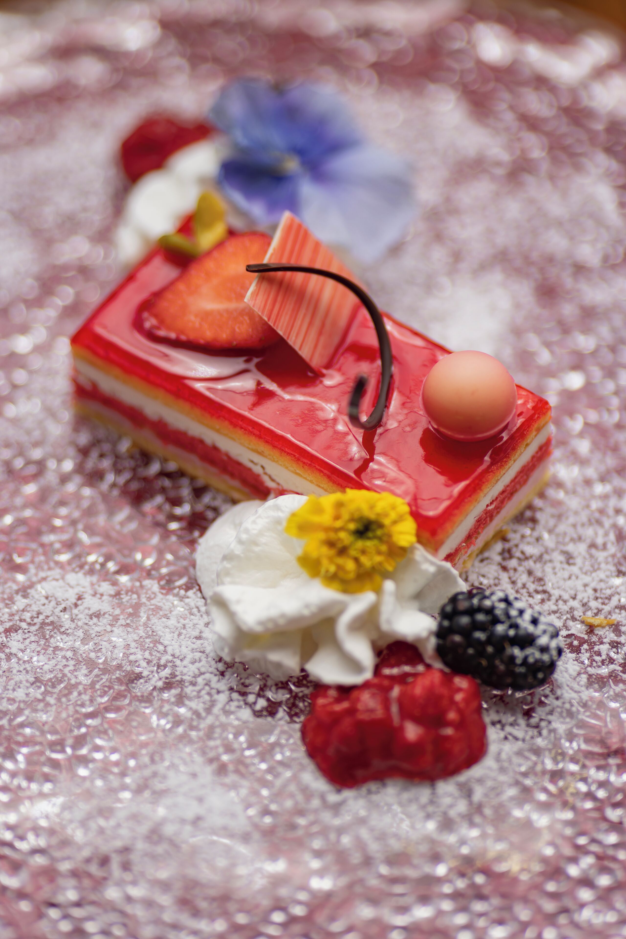 Un postre con fresas, un palito de chocolate y una cereza sobre una superficie texturizada.