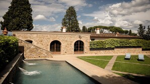 A stone building with a pool, arched windows, and a well-maintained lawn with lounge chairs. - Dimora Ghirlandaio (Impruneta)