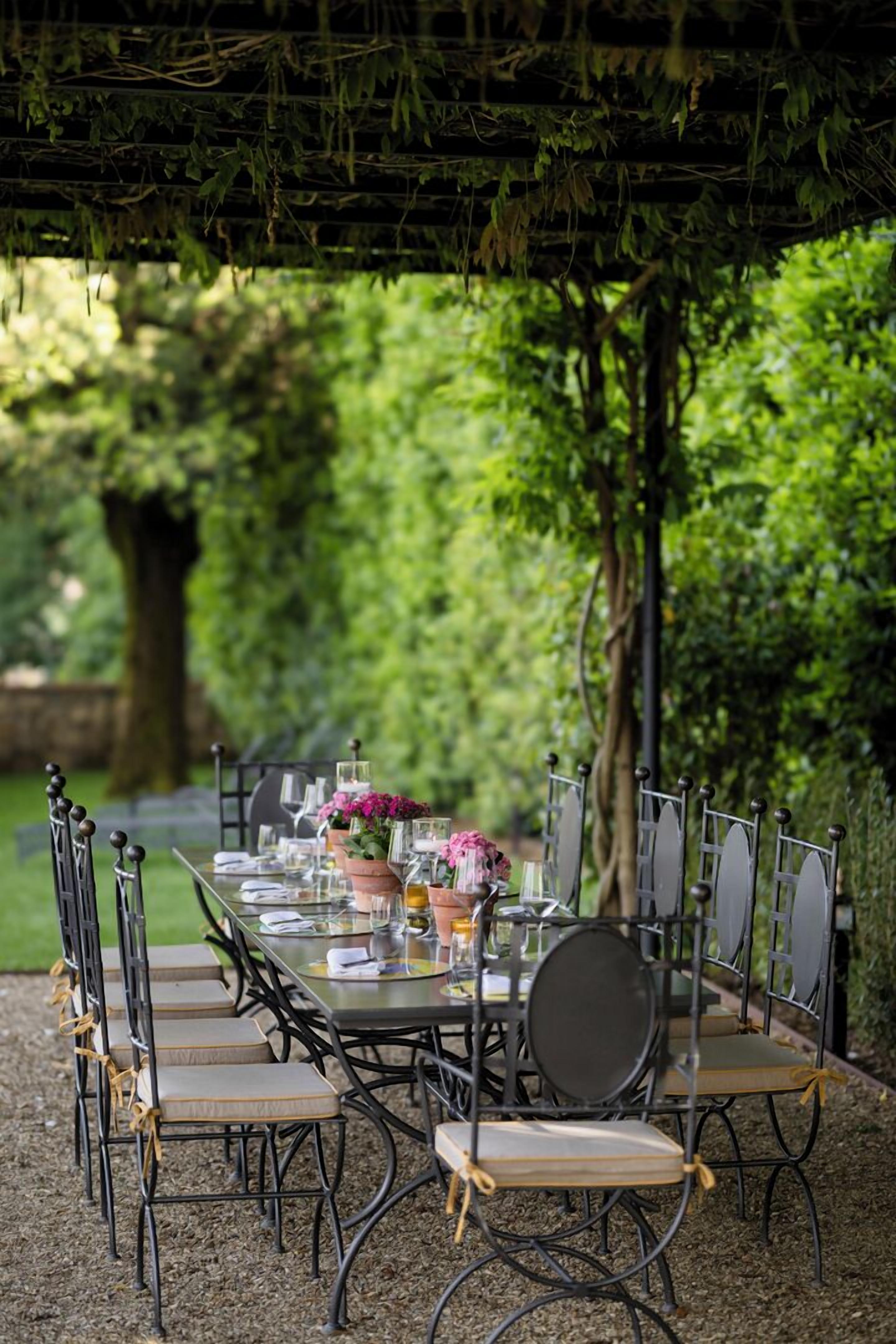 An outdoor dining area with a table set for six, surrounded by metal chairs with cushions.
