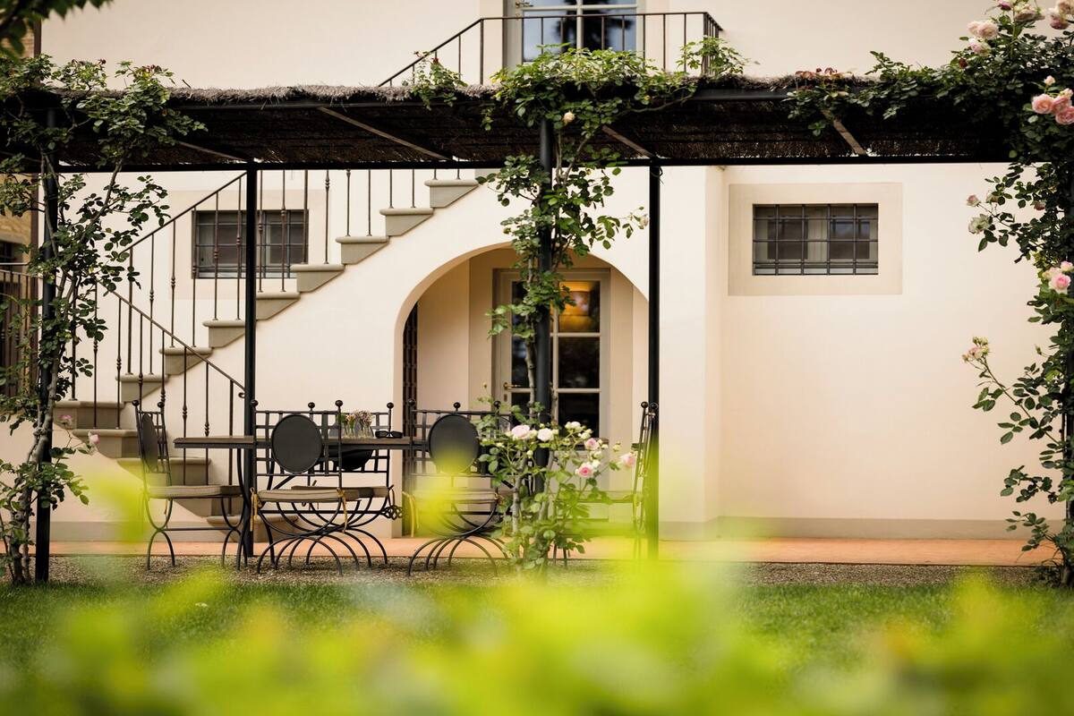 A building with a staircase, a covered outdoor seating area, and a garden.