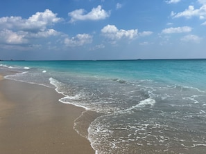 A beach with clear turquoise water and gentle waves.